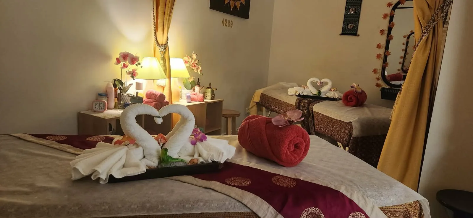 Twin Thai massage beds dressed with heart-shaped towel swans, red towels and orchids